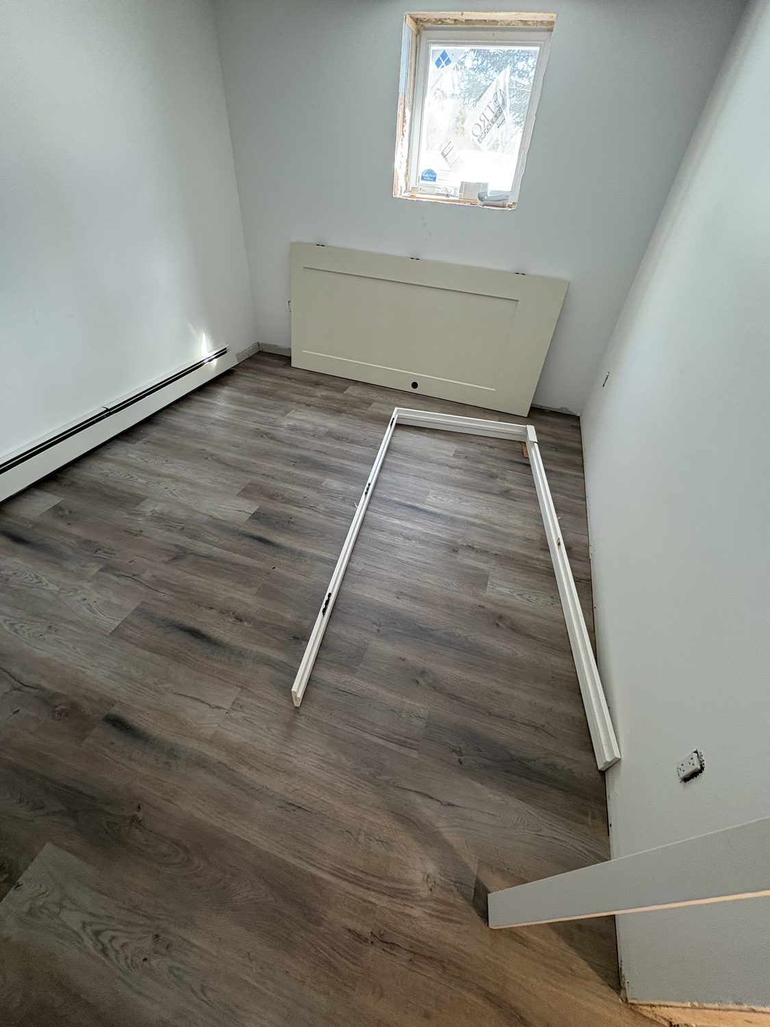 The same basement room with new wood-look vinyl plank flooring laid throughout