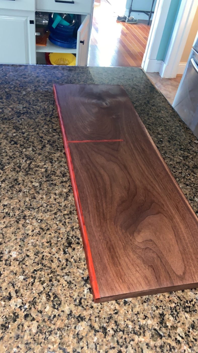 Solid walnut serving board with a red epoxy inlay running through the grain