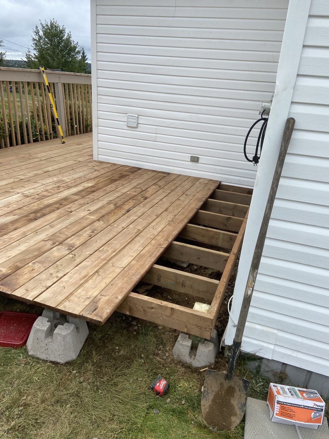 Deck under construction showing new joists on concrete piers and fresh decking boards