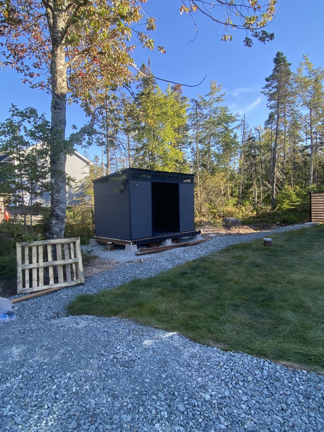Storage shed set level on a new gravel pad at the edge of the woods