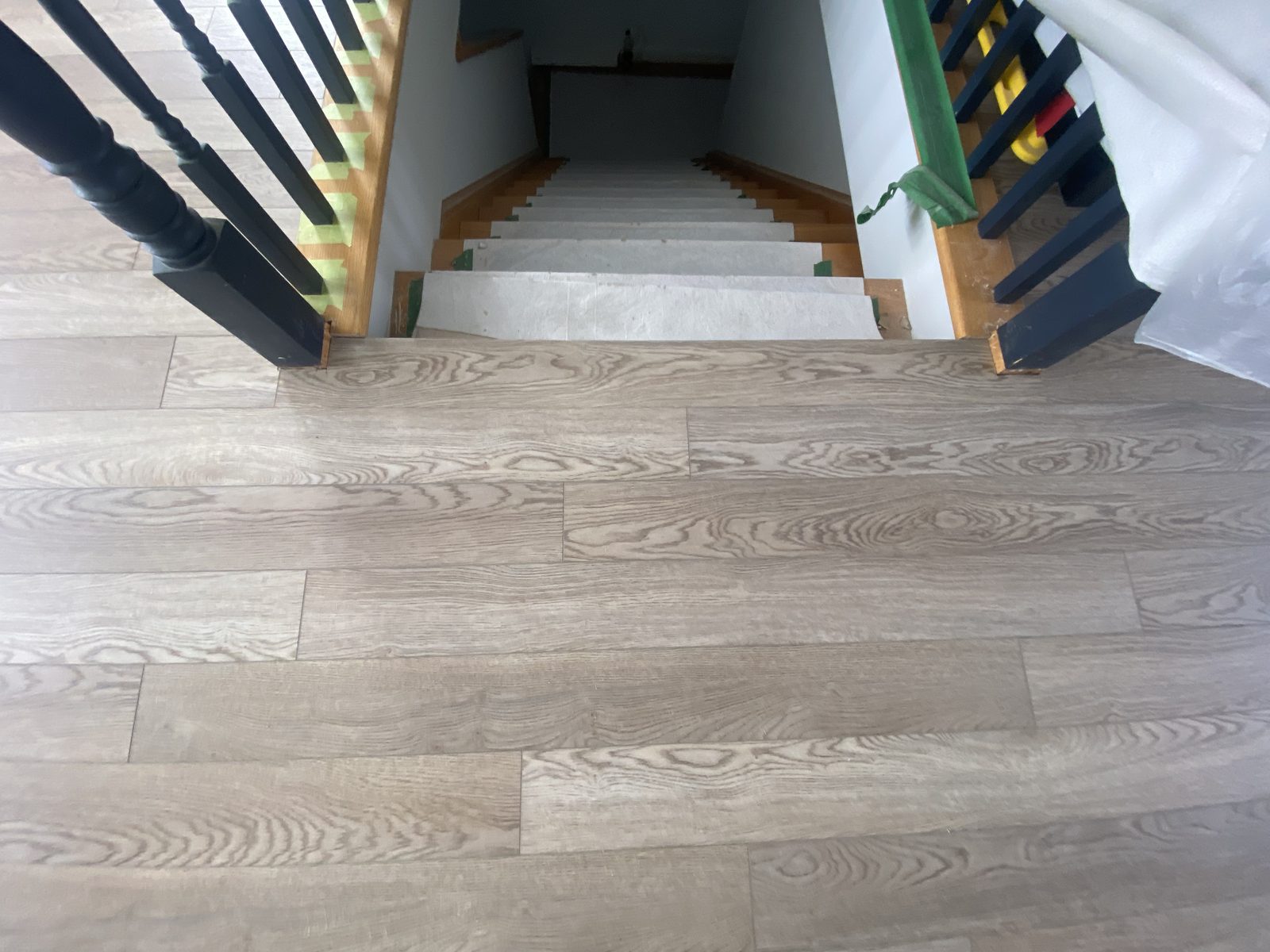 Plank flooring finished around a stair landing and railing